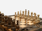 Overhead view of the carved chess board with the full set of light and dark wooden pieces in starting position