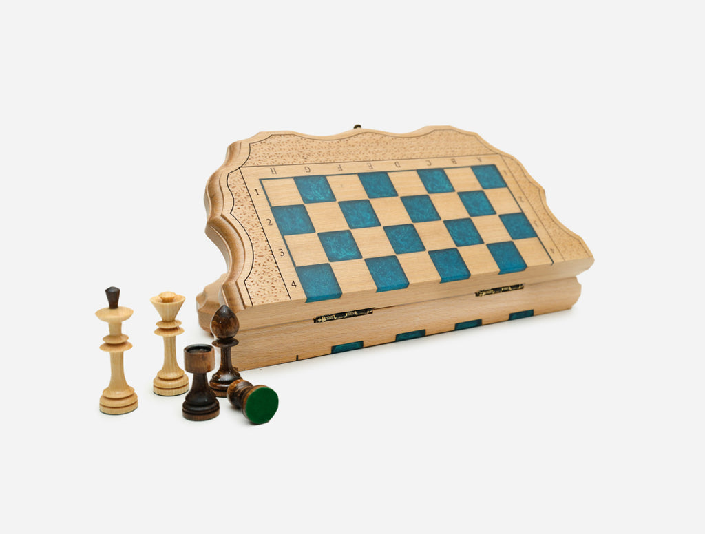 Compact folding chess board in pale wood with blue epoxy squares and wooden pieces, shown partly open