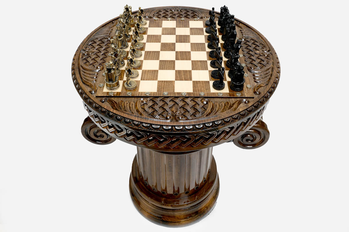 Overhead view of the round Crusaders chess table showing the full board, Celtic-knot carved apron and figural metal armies