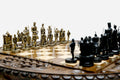 Close-up of the Crusaders chess pieces - a gold-brass army facing a black army of medieval knights, kings and castle rooks on the carved board