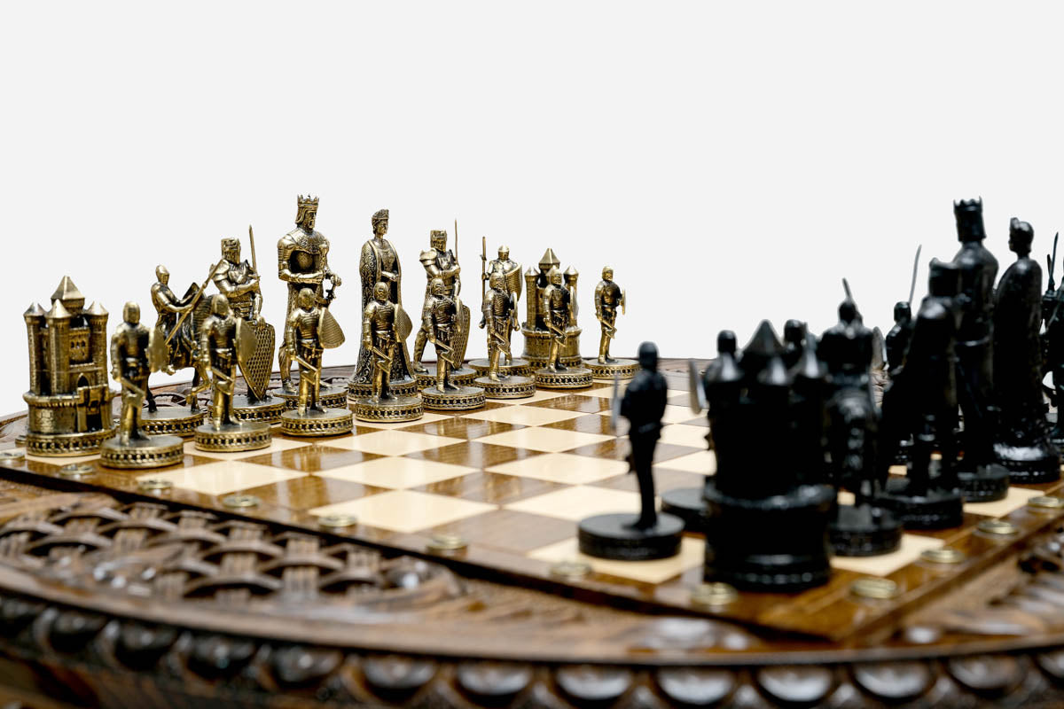 Close-up of the Crusaders chess pieces - a gold-brass army facing a black army of medieval knights, kings and castle rooks on the carved board