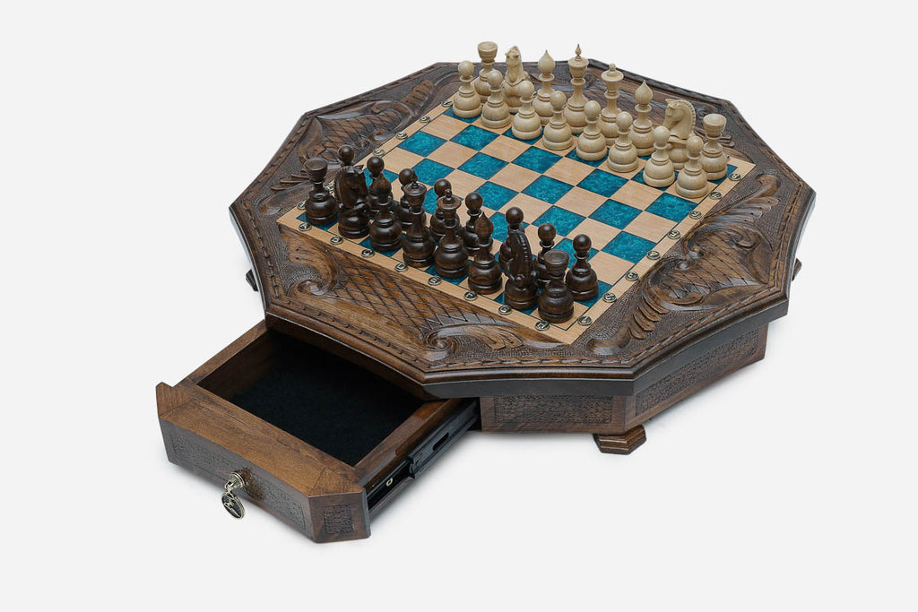 The octagonal chess set with its storage drawer pulled open, revealing black felt lining and a brass pendant pull