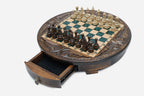 The round green-epoxy chess set with its storage drawer open, showing black felt lining and a brass pendant pull