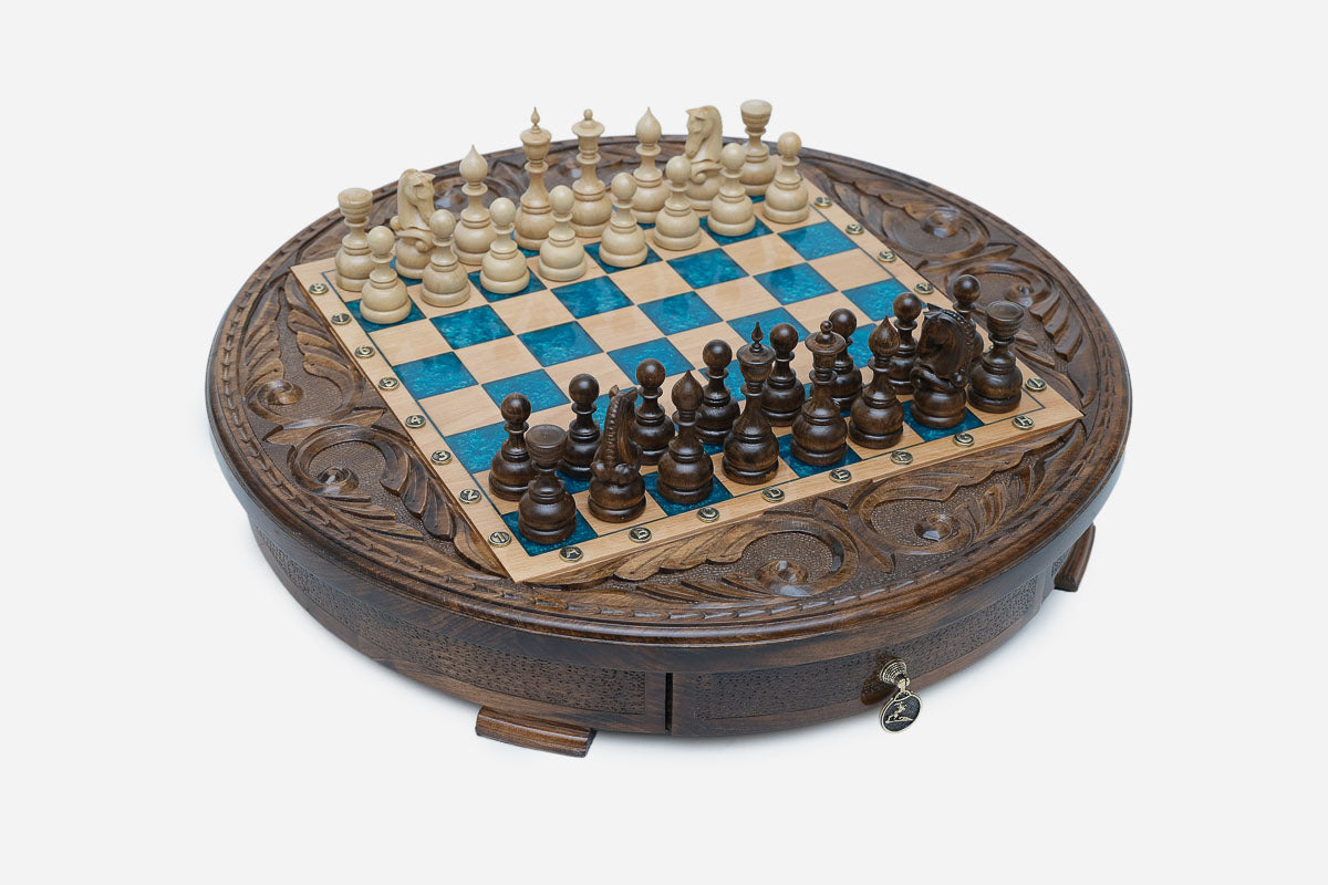 Full view of the round blue-epoxy chess board with light and dark wood pieces in starting position