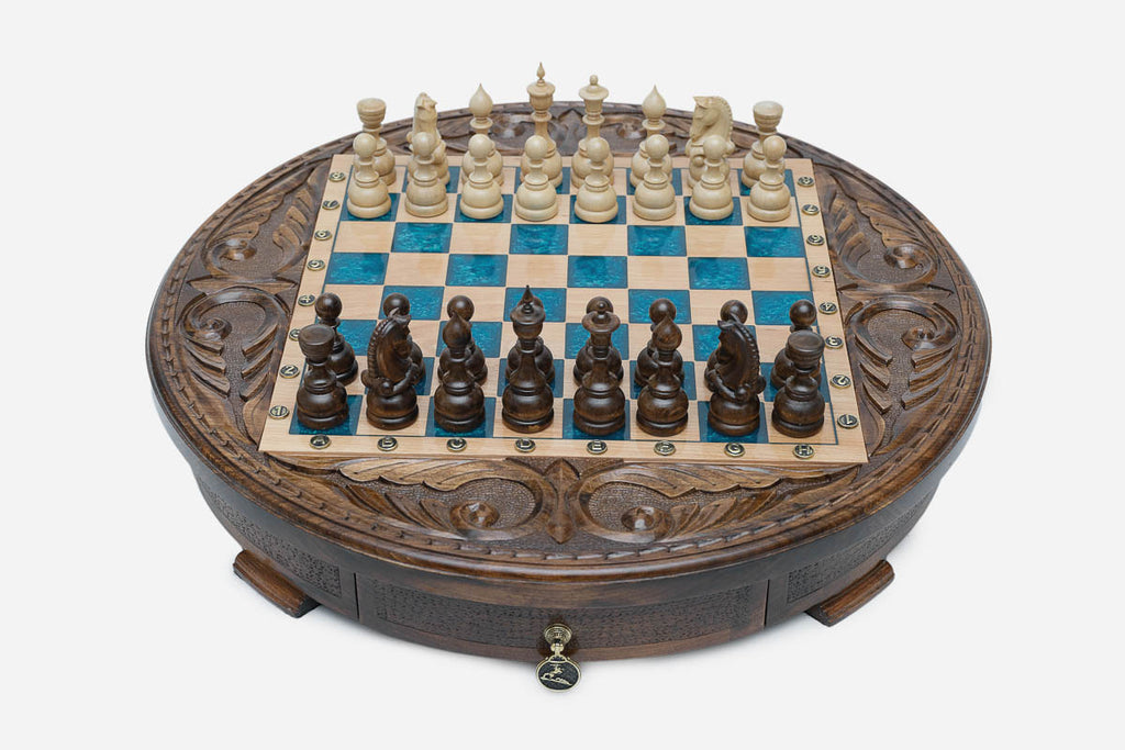 Round carved wooden chess set with turquoise-blue epoxy resin squares and wooden Staunton pieces set up for play