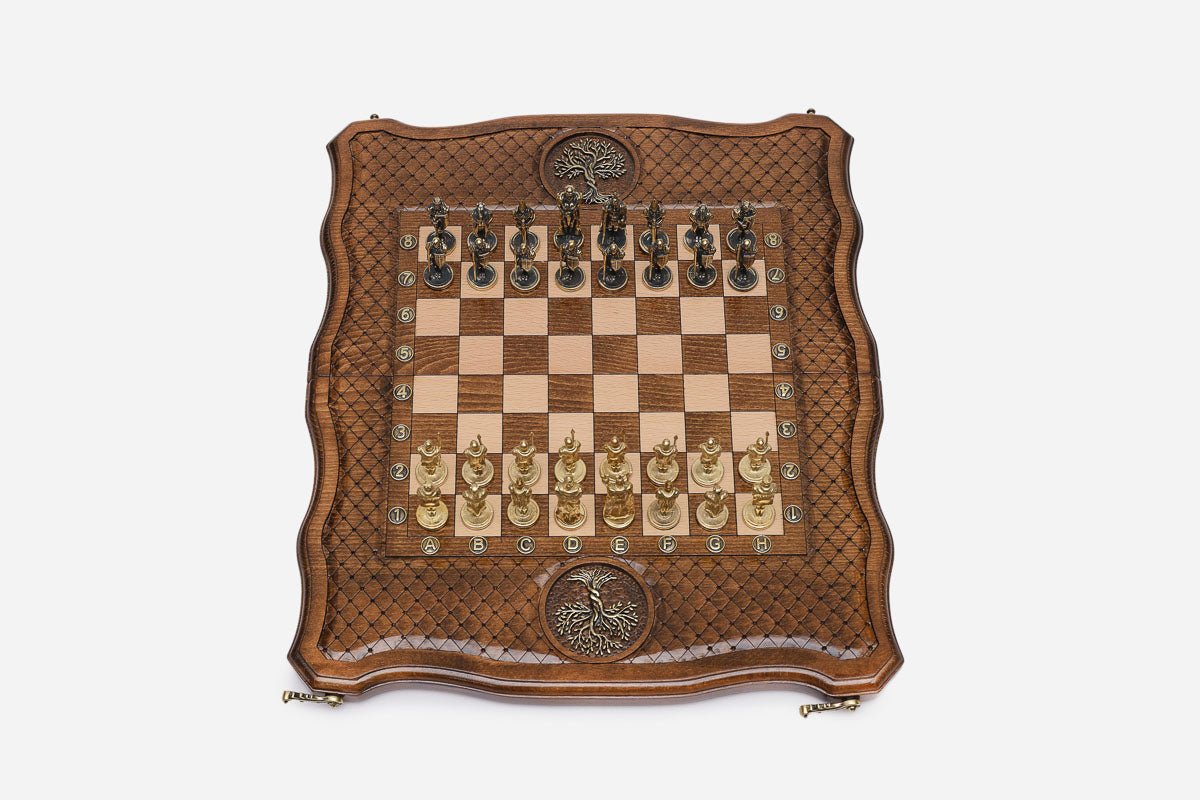 Overhead view of the wooden chess board with cast-metal medieval warrior pieces and bronze Tree of Life medallions
