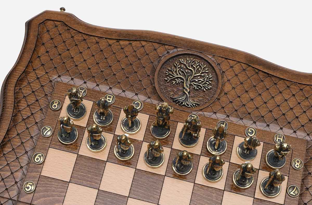 Close-up of the metal pawns beside an engraved bronze Tree of Life medallion inlaid in the wooden frame