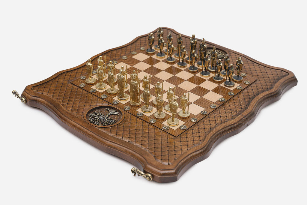 Angled view of the quilted beech board with figural chess pieces and a bronze Tree of Life medallion on the border