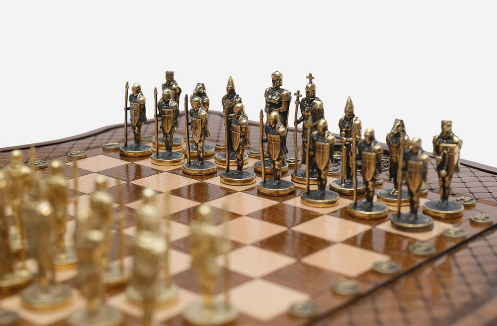 Detail of the ornate cast-metal soldier chess pieces facing off across the diamond-carved board
