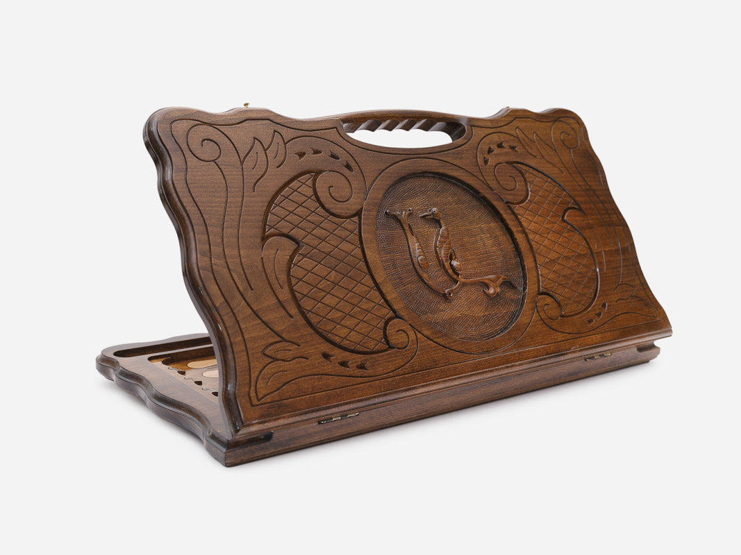 Carved beechwood backgammon board with symmetrical scrollwork and a central medallion, with a carry handle, propped open