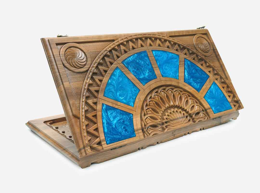 Folding walnut backgammon board with green and teal epoxy panels in a carved sunburst design, shown closed at an angle