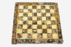 Top-down view of the empty marble and onyx chess board with glowing golden onyx squares and brass medallions