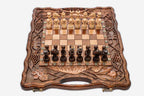 Folding walnut chess board carved with pomegranate and grape-vine motifs and beech and walnut pieces set up for play