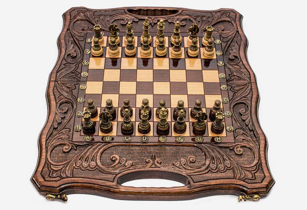 Folding walnut chess-backgammon board with deeply carved borders and ornate bronze chess pieces set up for play