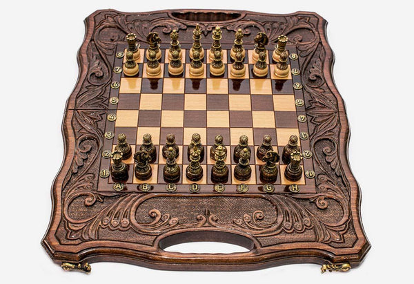 Folding walnut chess-backgammon board with deeply carved borders and ornate bronze chess pieces set up for play
