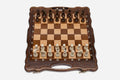 Folding walnut chess board with a scalloped frame, pebbled border and beech and walnut pieces in starting position