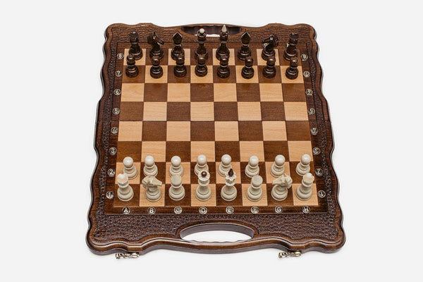 Folding walnut chess board with a scalloped frame, pebbled border and beech and walnut pieces in starting position