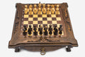 Compact dark walnut chess set with scroll-carved corners and Staunton pieces set up on the inlaid board