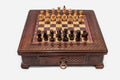 Compact wooden chess set with diamond-lattice carved border and Staunton pieces set up on the inlaid board