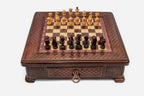 Compact wooden chess set with diamond-lattice carved border and Staunton pieces set up on the inlaid board