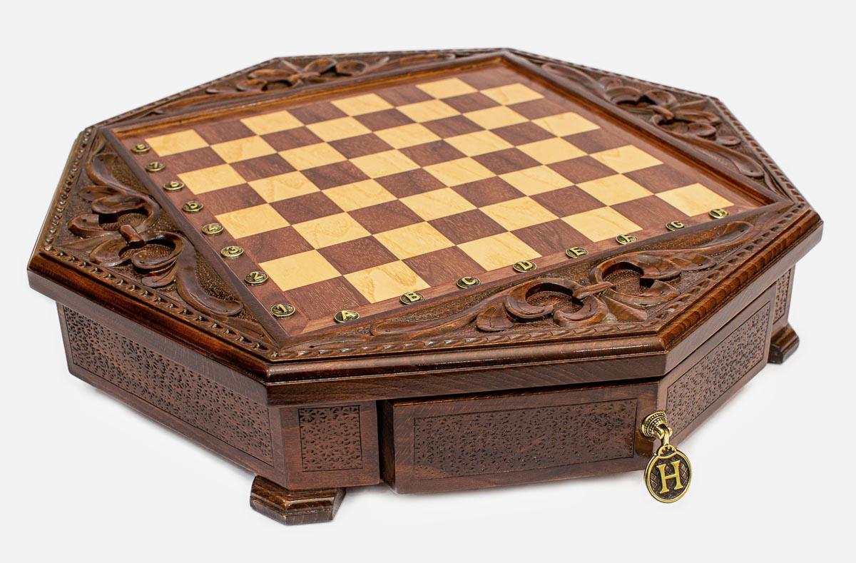 Angled view of the empty octagonal chess board with carved fleur-de-lis border and brass drawer pendant