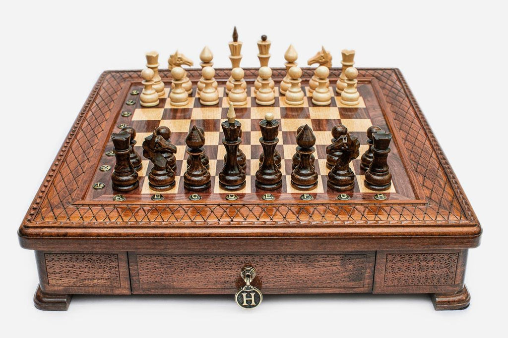 Square wooden chess set with carved diamond-lattice border and Staunton pieces set up on the walnut and maple board