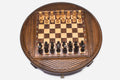 Round wooden chess set with woven lattice-carved border and Staunton pieces set up on the inlaid board