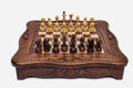 Handmade wooden chess set with carved scalloped frame and Staunton pieces arranged on the walnut and maple board
