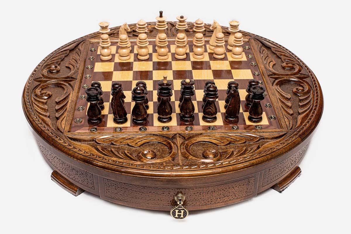 Angled view of the round carved chess set with dark and light Staunton pieces arranged on the board
