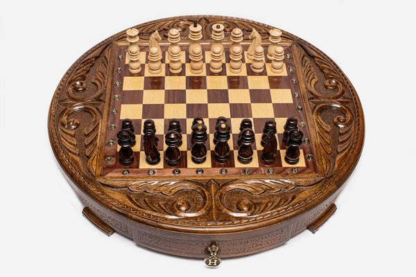 Round handmade wooden chess set with walnut and maple inlaid board and carved Staunton pieces set up for play