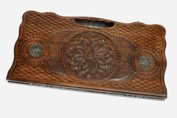 Carved beechwood backgammon board with a central rosette mandala and bronze roundels, propped open