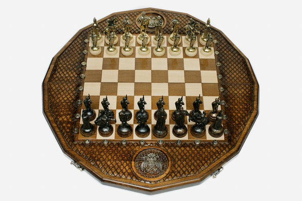 Twelve-sided carved chess board with a Russian double-headed-eagle medallion and ornate bronze figural pieces set up for play