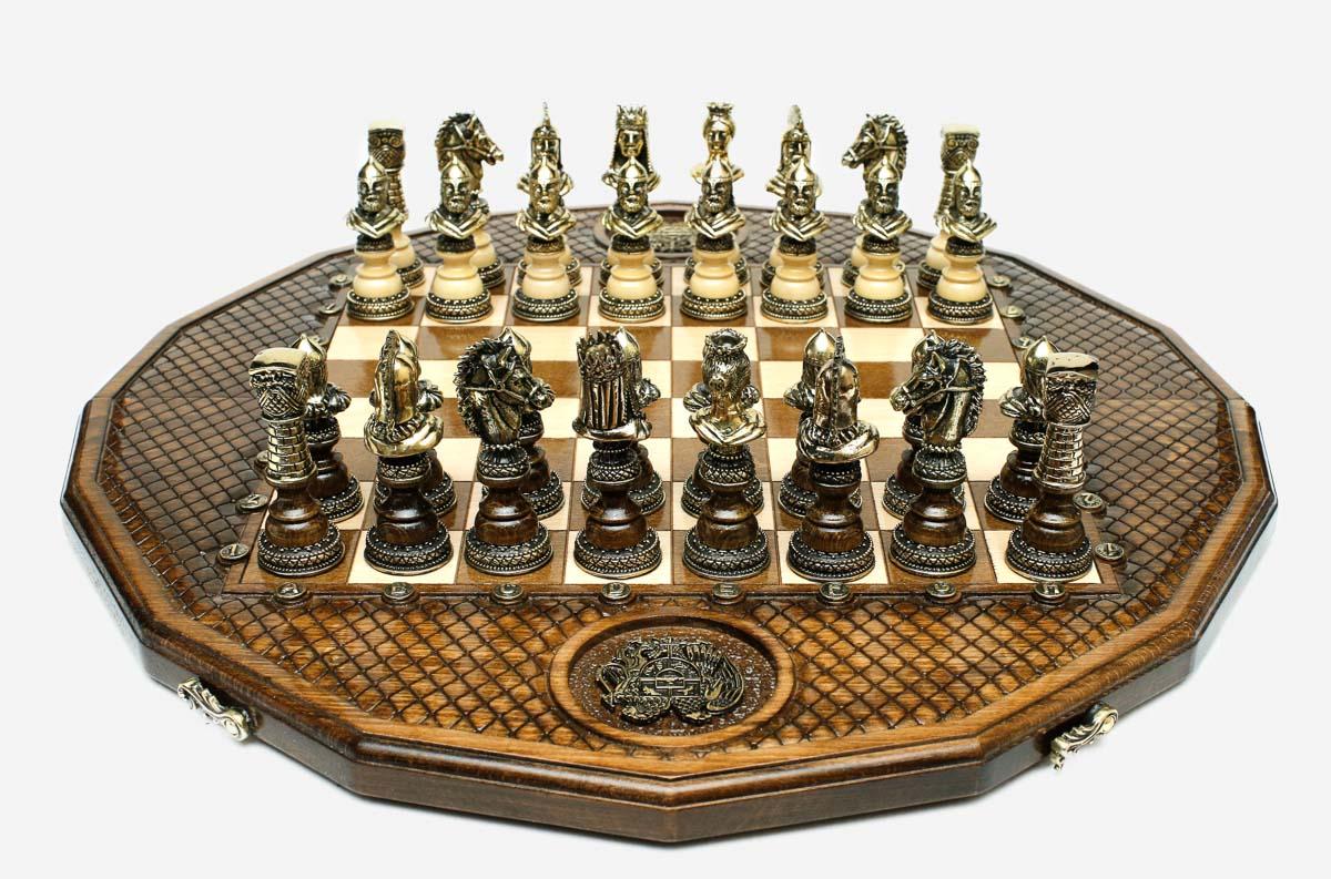Twelve-sided carved chess board with an inlaid coat-of-arms medallion and ornate bronze figural pieces set up for play