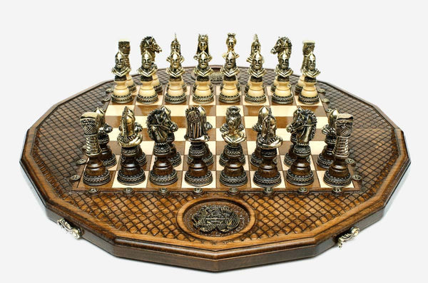 Twelve-sided carved chess board with an inlaid coat-of-arms medallion and ornate bronze figural pieces set up for play