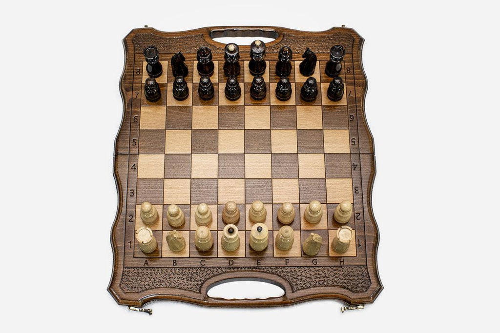 Folding walnut chess board with a lattice border, carry-handle cutout and beech and walnut pieces in starting position