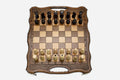 Folding walnut chess board with a lattice border, carry-handle cutout and beech and walnut pieces in starting position