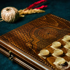 Chip-carved eternity ornament detail on the handmade wooden backgammon board with playing pieces