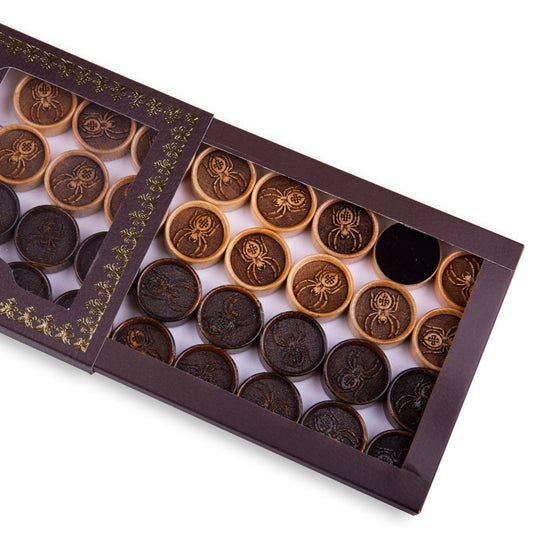 Close-up of wooden backgammon pieces with an engraved spider design.
