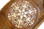 Close-up of the pale snowflake ornament with scroll arms on the stippled panel and rope ring