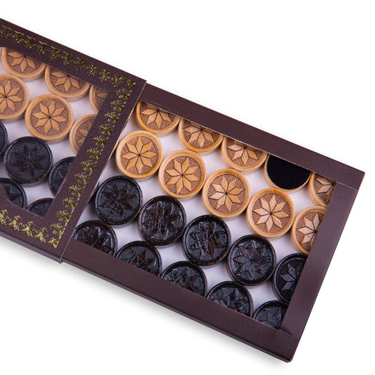 Close-up of wooden backgammon pieces with an engraved octagram star design.