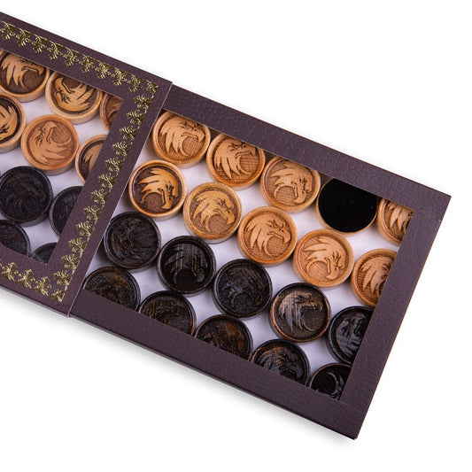 Close-up of wooden backgammon pieces with an engraved eagle design.
Set