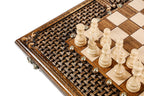 Light hand-carved chess pieces on the wooden chess board with carved braid border