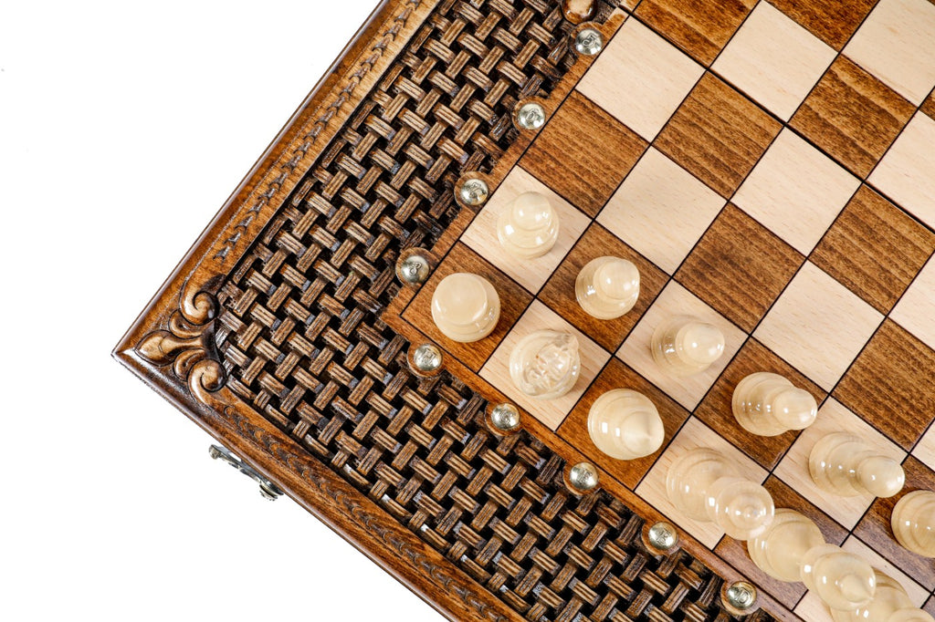 Close view of the woven braid carving and light chess pieces at the board edge