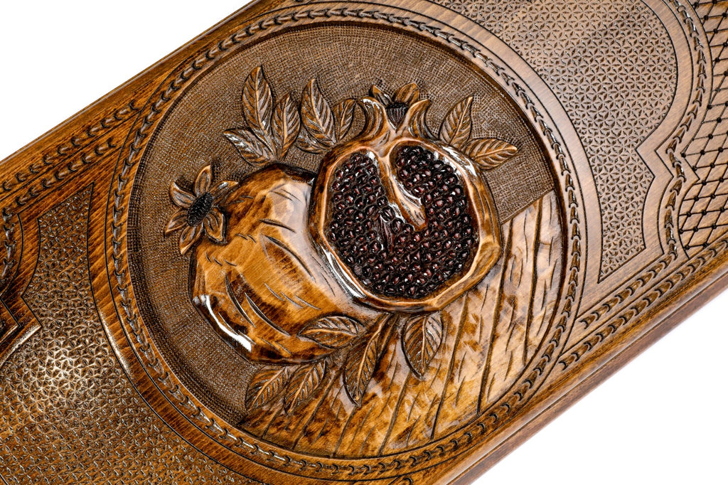 Detail view of the textured pomegranate relief on the solid wood exterior.
