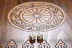 Close-up of the carved wheel ornament and dice on the wooden backgammon field