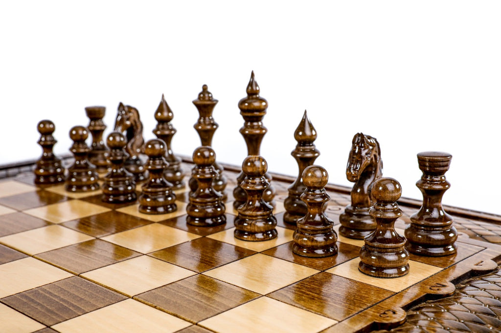 Dark hand-carved chess pieces on the beech and walnut squares of the large chess board