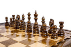 Dark hand-carved chess pieces on the beech and walnut squares of the large chess board