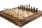 Large handmade chess board with carved lattice border and hand-carved wooden pieces, close angle