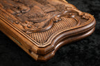 Edge of the closed walnut board with the cast-bronze clasp and the carved scroll frame