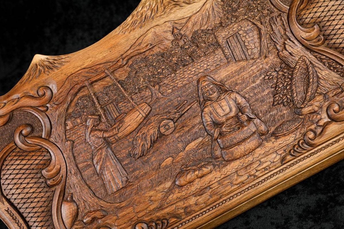 Close-up of the village scene: woman turning the hand mill, houses and orchards carved in deep relief